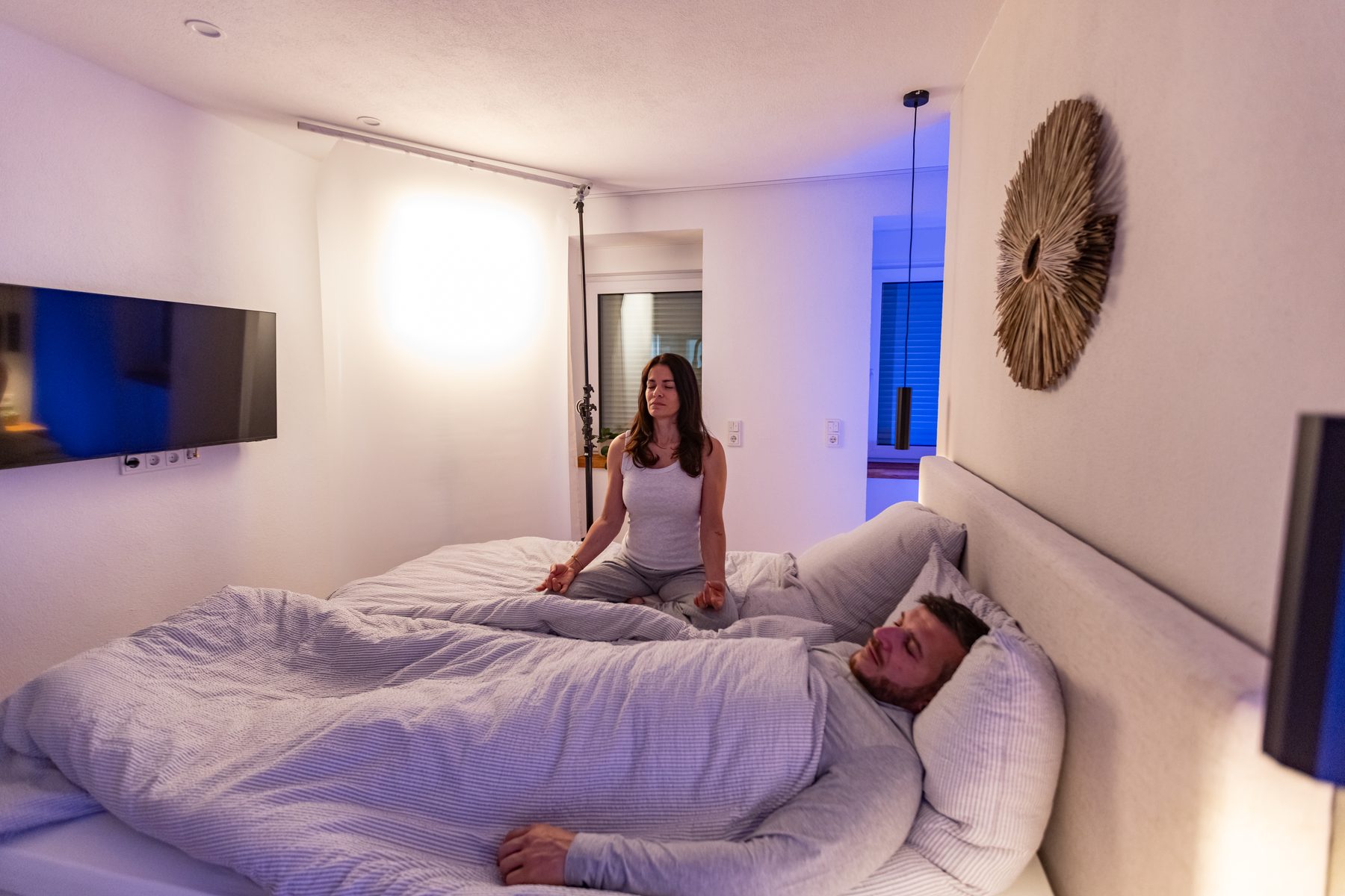 Darstellerin im blau beleuchteten Schlafzimmer Set zwischen zwei Takes beim LunaSol Werbespot