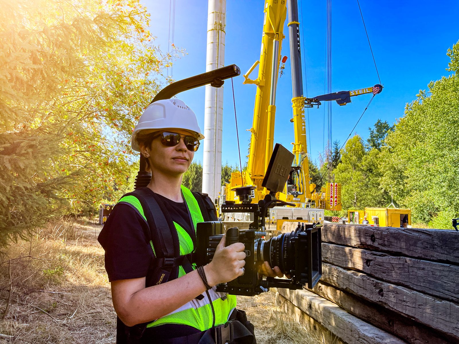 Making of beim Casar Industrieimagefilm in Kirkel, Kamerafrau mit Cinema Setup und Schutzausrüstung vor dem Schwerlastkran auf der Windkraftbaustelle im Saarland