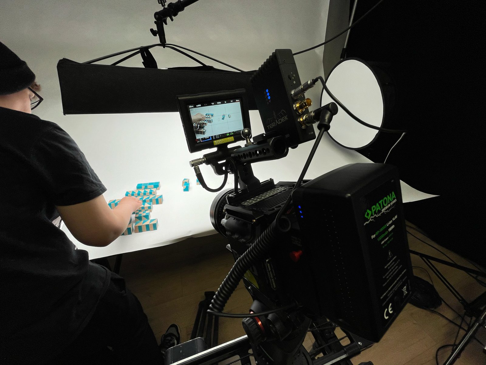 RED Cinema 6K mit Feldmonitor auf dem Stativ während des Studiodrehs für den ROMBI TV Werbespot, Patona Akku und Stop Motion Setup im Hintergrund